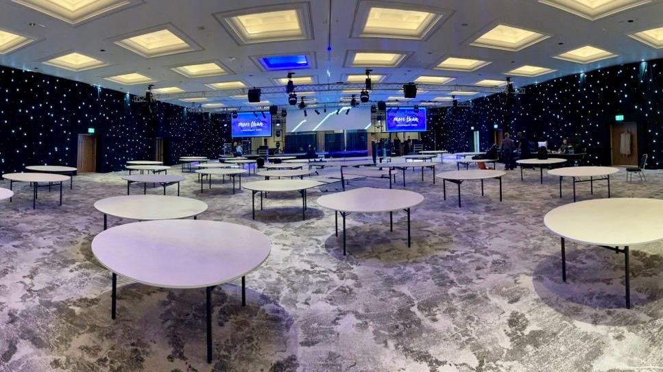 A vast event hall transformed with a black LED starcloth wall, laid for a gala dinner
